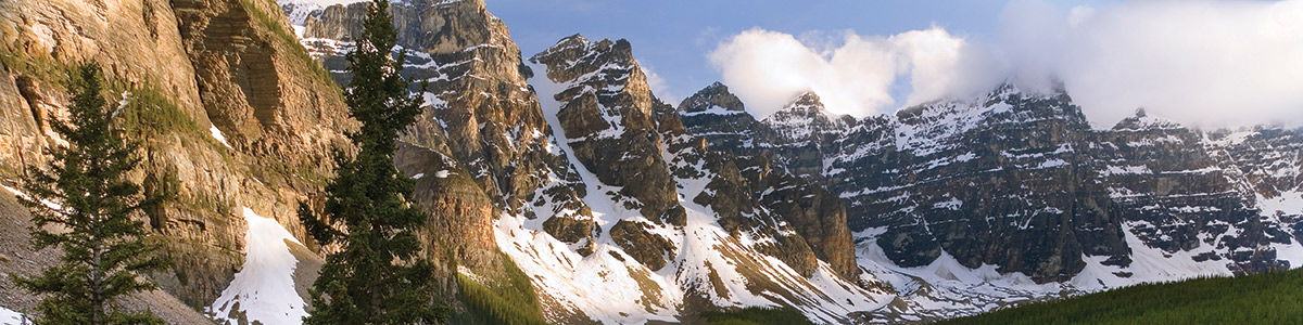 Panoramic view of the snow-capped Rocky Mountains with green grass in the foreground